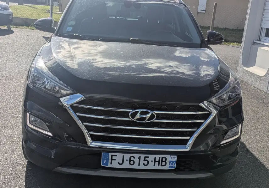 Vue frontale d'un Hyundai Tucson noir 2019 avec calandre chromée et phares LED, stationné en extérieur.