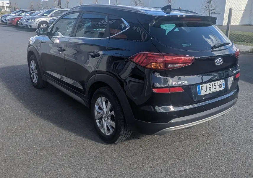 Hyundai Tucson noir vue 3/4 arrière droit, feux arrière LED et jantes alliage visibles, stationné en extérieur.