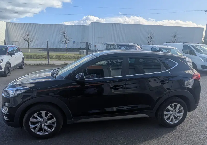 Vue de profil côté gauche d'un Hyundai Tucson noir 2019 garé sur un parking extérieur.