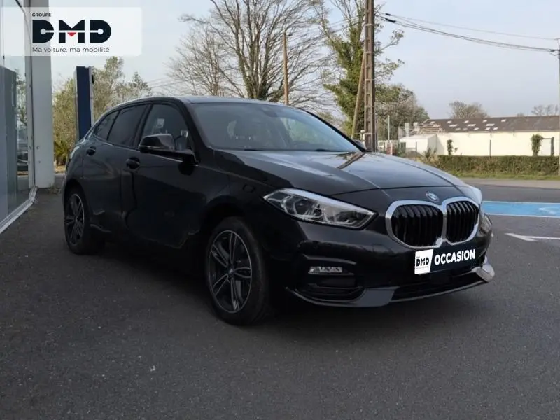 BMW Série 1 118iA 2024 en saphirschwarz métallisé vue 3/4 avant avec calandre et jantes alu distinctives.