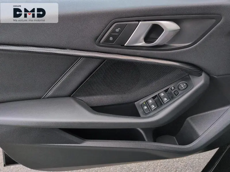 Détail de la porte intérieure côté gauche de la BMW Série 1 118iA 2024 en Saphirschwarz avec commandes électriques et poignée argentée.