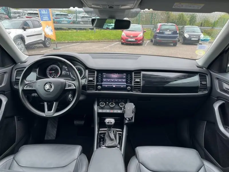 Vue intérieure avant du Skoda Kodiaq noir Magic Nacré, tableau de bord moderne avec écran tactile et volant cuir multifonctions.