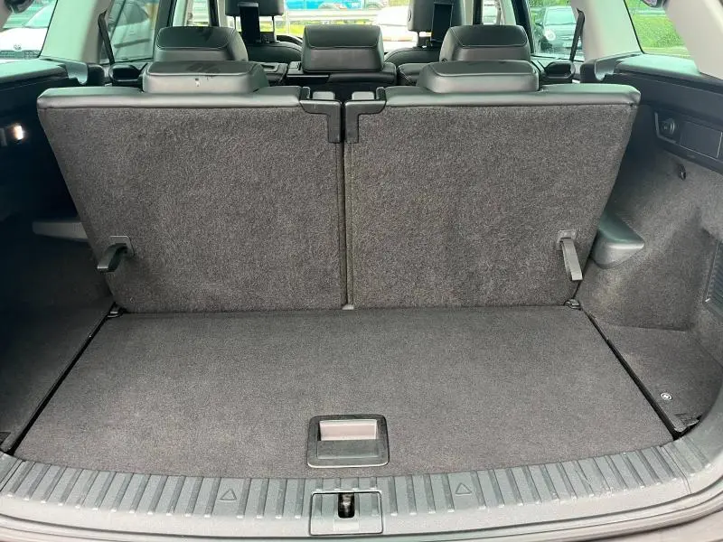 Vue du coffre arrière du Skoda Kodiaq noir Magic Nacré avec la troisième rangée de sièges relevée, intérieur en tissu gris.