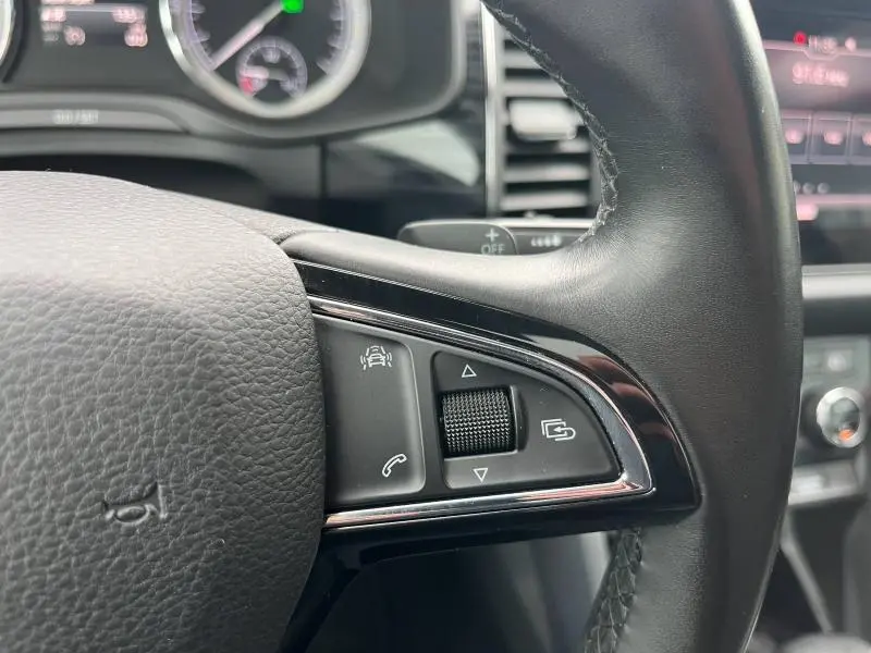 Gros plan sur les commandes gauche du volant cuir noir du Skoda Kodiaq 2018, avec molette et boutons multifonctions.