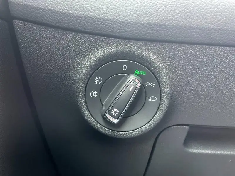 Gros plan sur le bouton de commande des phares noir dans l’habitacle du Skoda Kodiaq, avec mode automatique activé.