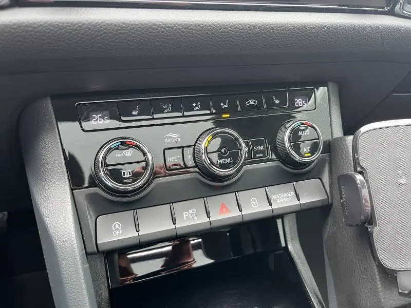 Vue rapprochée de la console centrale noire brillante du Skoda Kodiaq 2018, avec commandes climatisation tri-zone et boutons fonctionnels.