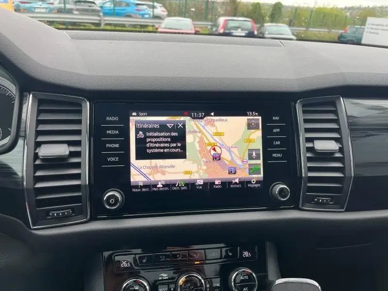 Vue intérieure du tableau de bord du Skoda Kodiaq noir Magic Nacré, avec écran tactile affichant la navigation GPS.