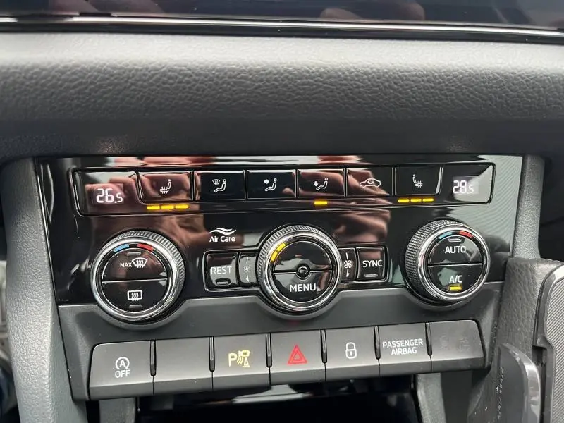 Vue rapprochée du panneau de commande de la climatisation automatique tri-zone du Skoda Kodiaq noir, avec réglages chauffants visibles.