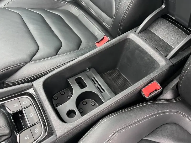 Vue rapprochée de la console centrale noire en cuir et plastique du Skoda Kodiaq 2018, avec porte-gobelets et accoudoirs.