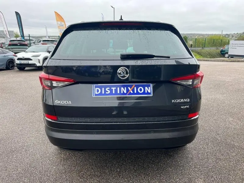 Vue arrière d'un Skoda Kodiaq noir Magic Nacré avec logo et plaques distinctives sur un parking extérieur.