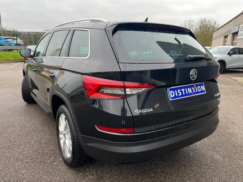 Vue 3/4 arrière droite d'un Skoda Kodiaq noir Magic Nacré avec feux arrière LED et barres de toit argentées.