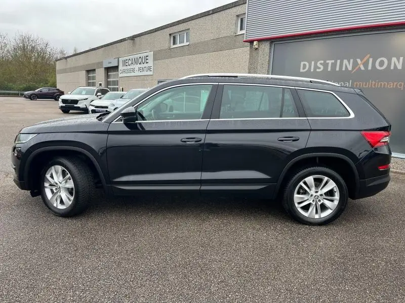 Vue latérale droite d'un Skoda Kodiaq noir Magic Nacré, SUV 7 places avec jantes alliage et barres de toit argentées.
