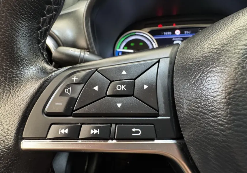 Gros plan sur les commandes multifonctions du volant cuir noir du Nissan Juke Hybrid 143 Business+ 2023.