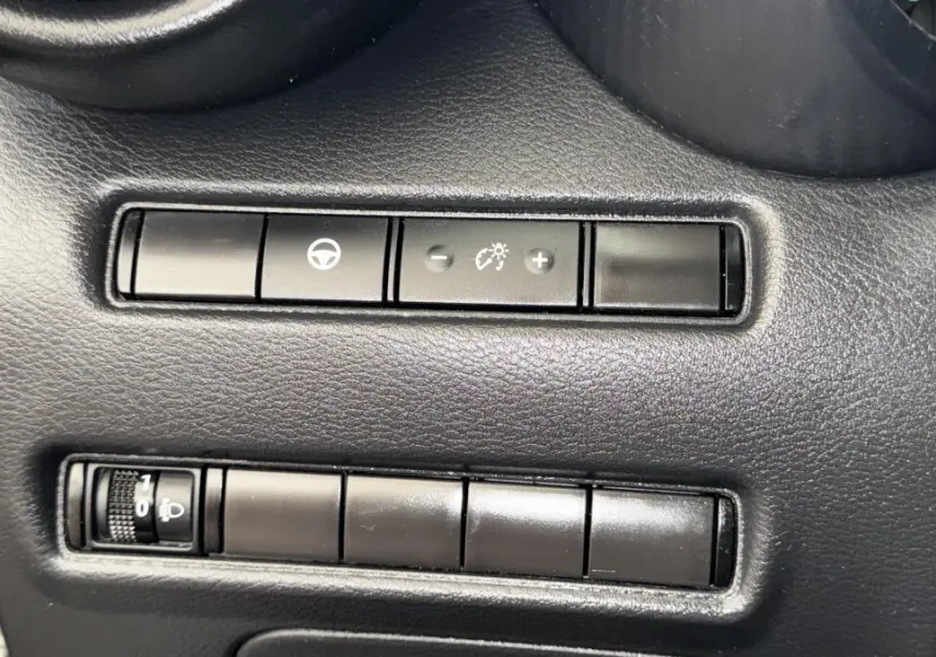 Gros plan sur les commandes noires du tableau de bord du Nissan Juke Hybrid 143 Business+ gris foncé, 2023.
