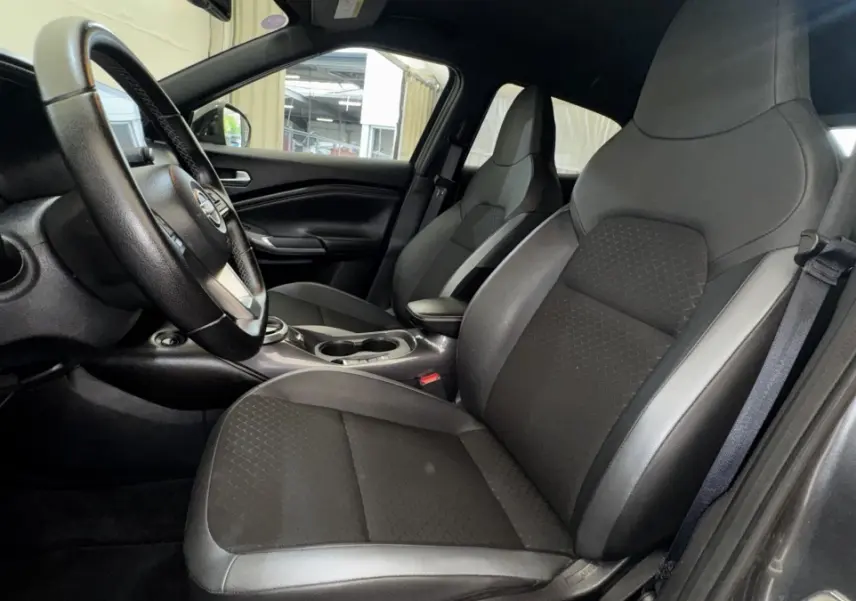 Intérieur Nissan Juke Hybrid gris foncé, vue côté conducteur, sièges avant en cuir et tissu, volant multifonctions.