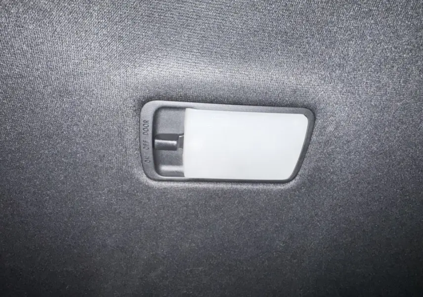 Plafonnier intérieur avec interrupteur de commande, éclairage blanc sur fond de tissu gris foncé.