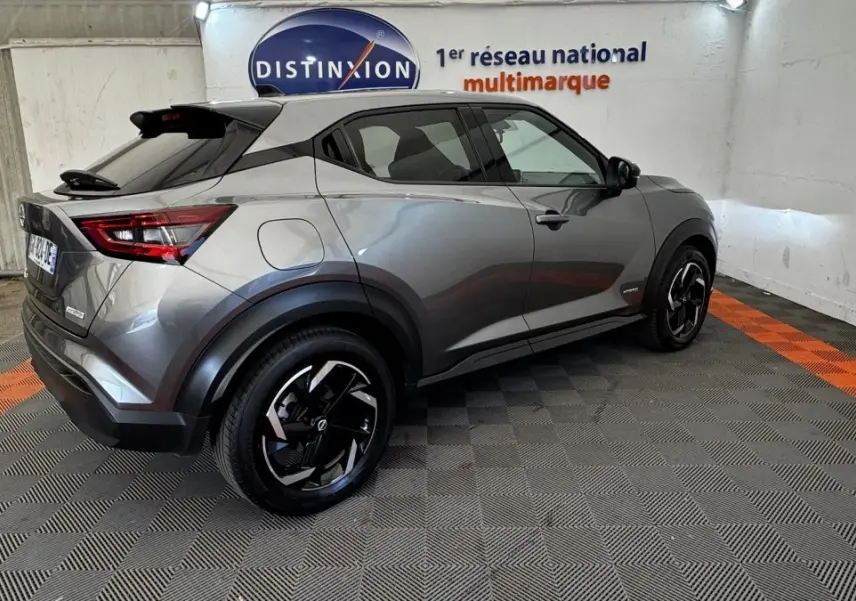 Nissan Juke Hybrid 143 Business+ gris foncé vu en 3/4 arrière droit avec jantes noires et toit noir.