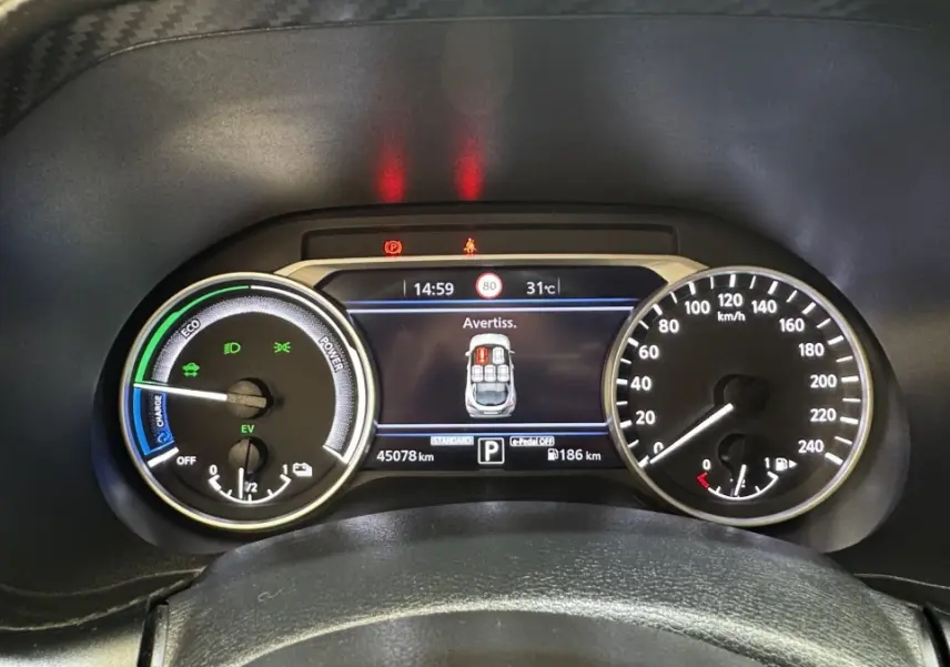 Vue rapprochée du combiné d'instruments numérique et analogique du Nissan Juke Hybrid 143 Business+ affichant une alerte de porte ouverte.