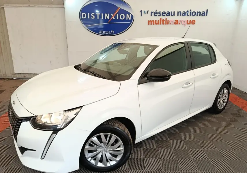 Peugeot 208 blanc vue 3/4 avant droit, phares allumés, rétroviseur noir et jantes alliage visibles.