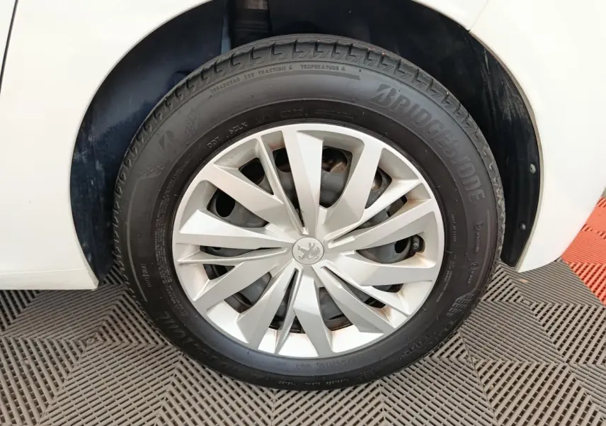 Gros plan sur la roue avant droite d'une Peugeot 208 blanche, avec jante en alliage et pneu Bridgestone.