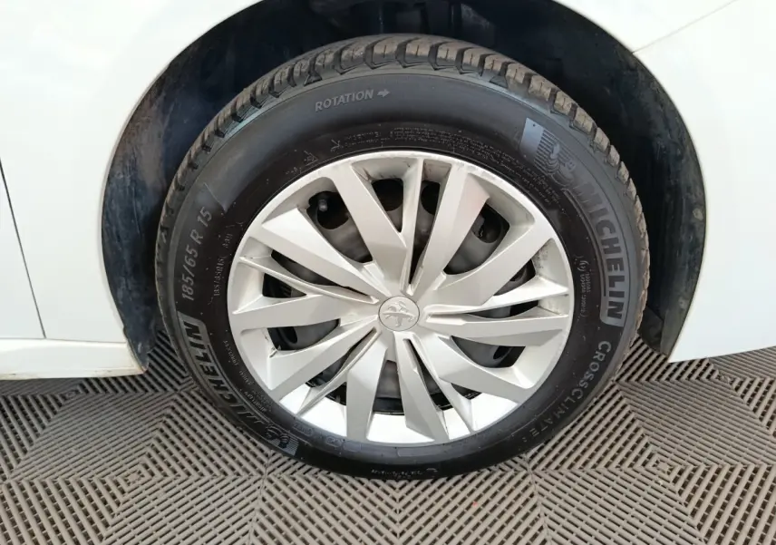 Gros plan sur la roue avant gauche d'une Peugeot 208 blanche avec jante en alliage et pneu Michelin.