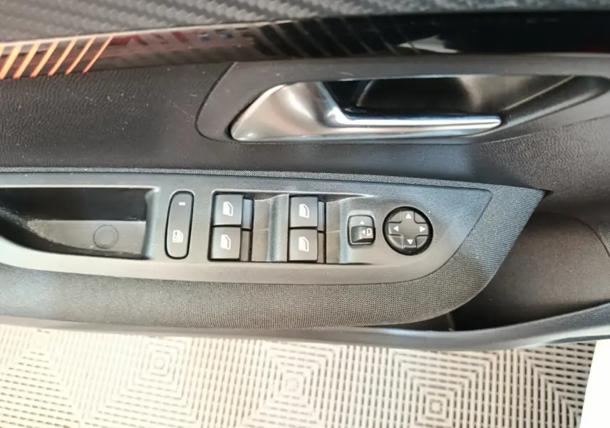 Gros plan sur la commande des vitres et rétroviseurs côté gauche intérieur d’une Peugeot 208 blanche 2023.
