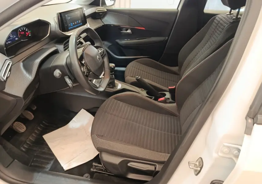 Vue intérieure côté conducteur de la Peugeot 208 blanche 2023, avec volant cuir multifonctions et tableau de bord digital.