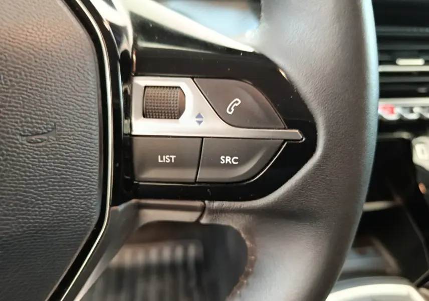 Gros plan sur les commandes gauche du volant cuir noir de la Peugeot 208 1.5 BlueHDi 100 S&S Premium 2023.