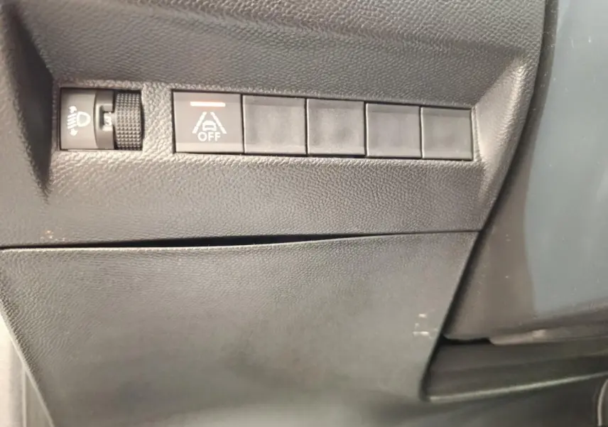 Détail intérieur montrant les commandes de réglage des phares et désactivation de l’assistance au maintien de voie sur Peugeot 208.