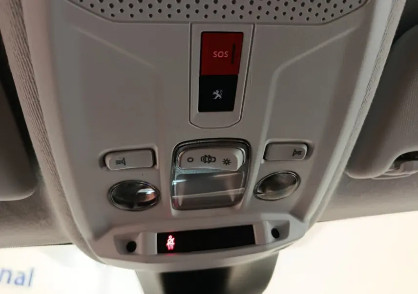 Vue rapprochée du panneau de commandes au plafond intérieur de la Peugeot 208 blanc, avec bouton SOS rouge et éclairage intégré.