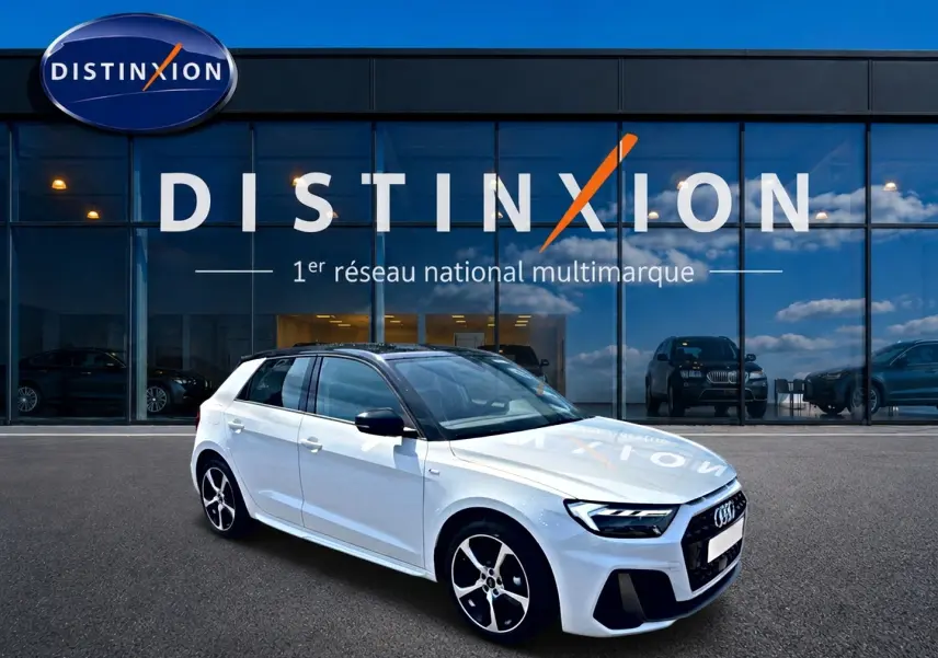 Audi A1 Sportback blanc et noir en 3/4 avant droit devant une vitrine avec logo Distinxion.