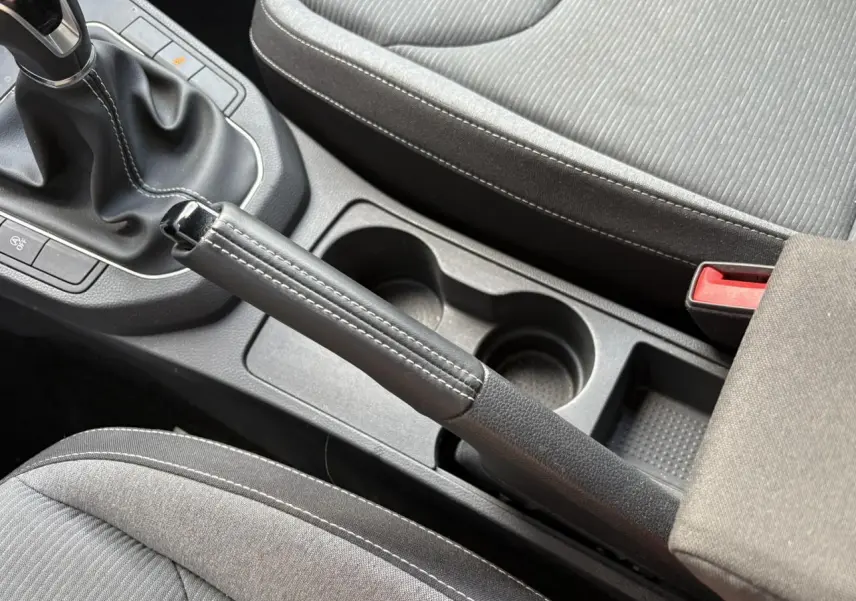 Vue rapprochée de la console centrale de la SEAT IBIZA blanche 2025, montrant frein à main cuir et sièges gris.