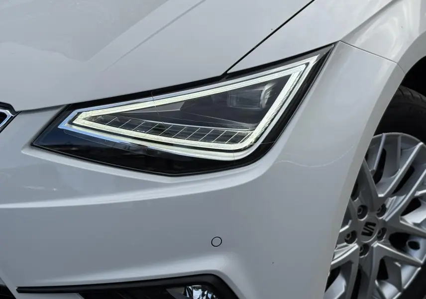 Gros plan sur le phare avant droit et la jante alliage 16 pouces d'une SEAT Ibiza blanche 2025 finition Xcellence.
