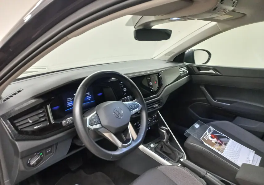 Vue intérieure côté conducteur du Volkswagen Taigo 2025, tableau de bord noir avec volant multifonction et console centrale moderne.