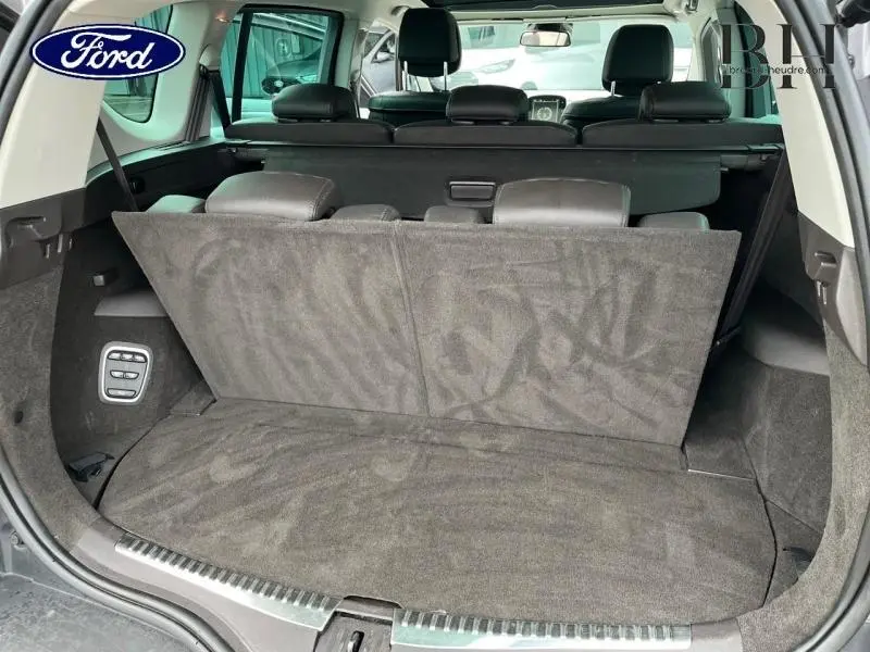 Vue arrière du coffre ouvert d'un Renault Espace gris Cassiopée avec sièges arrière rabattables et habillage intérieur sombre.