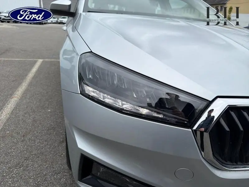 Gros plan sur le phare avant gauche d'une Skoda Fabia 2023 gris argent métallisé, mettant en valeur la calandre chromée.