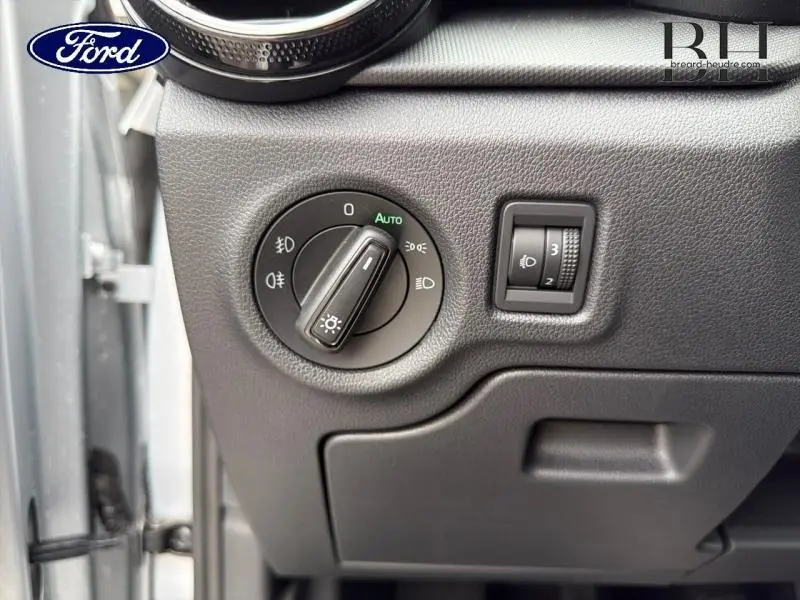 Gros plan sur le bouton de commande des phares et réglage d'intensité sur tableau de bord gris d'une Skoda Fabia 2023.