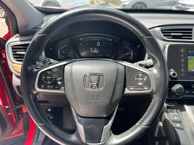 Vue rapprochée du volant cuir multifonction d’un Honda CR-V Rouge Rallye avec tableau de bord numérique et inserts bois.