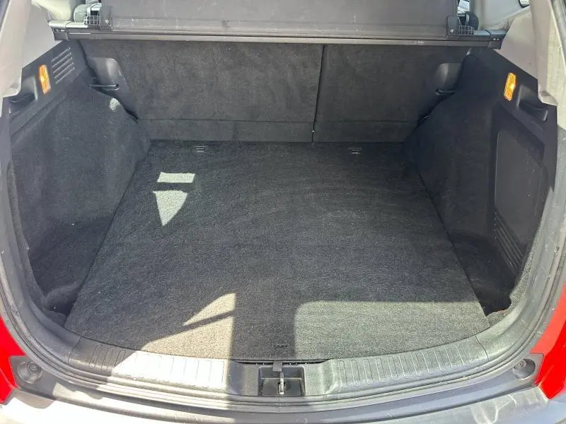 Vue intérieure du coffre spacieux du Honda CR-V rouge Rallye, avec revêtement noir et éclairage latéral intégré.