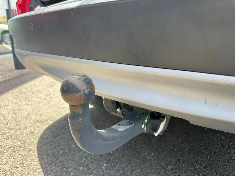 Gros plan sur l'attelage arrière rouillé du Honda CR-V rouge Rallye, avec pare-chocs gris et partie inférieure noire.