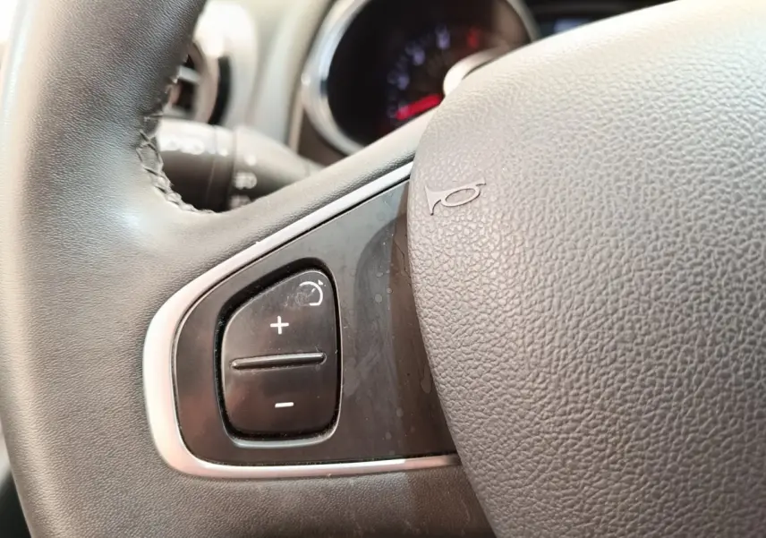 Gros plan sur le volant cuir noir de la Renault Clio Business dCi 75, montrant les commandes de régulateur de vitesse.