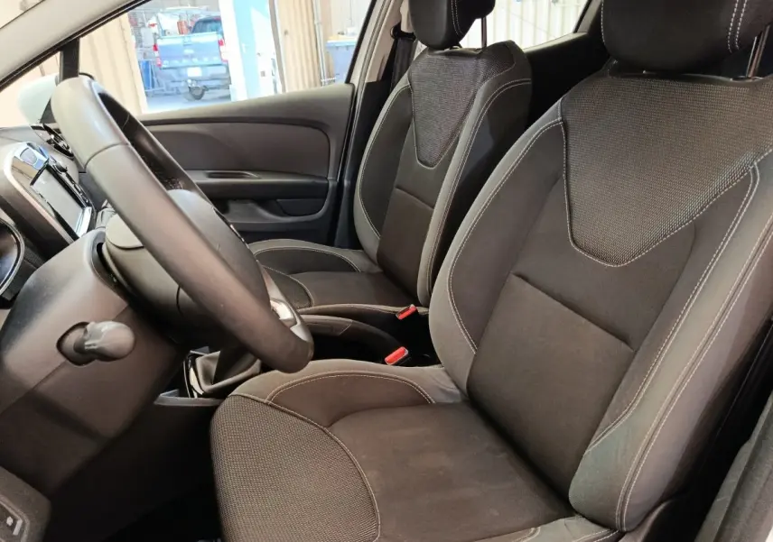 Vue intérieure côté conducteur de la Renault Clio Business 2018, sièges tissu noirs et volant cuir multifonctions.
