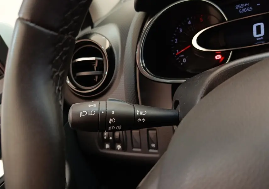 Gros plan sur la manette des feux à gauche du volant cuir dans l’habitacle d’une Renault Clio Business blanc 2018.