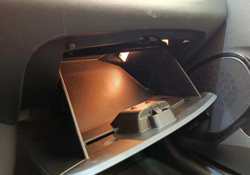 Vue rapprochée de la boîte à gants ouverte avec éclairage intérieur dans une Renault Clio Business dCi 75 blanche de 2018.