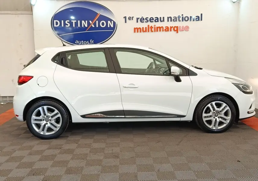 Profil droit d'une Renault Clio Business dCi 75 blanche, avec jantes alliage et rétroviseurs électriques dans un showroom.