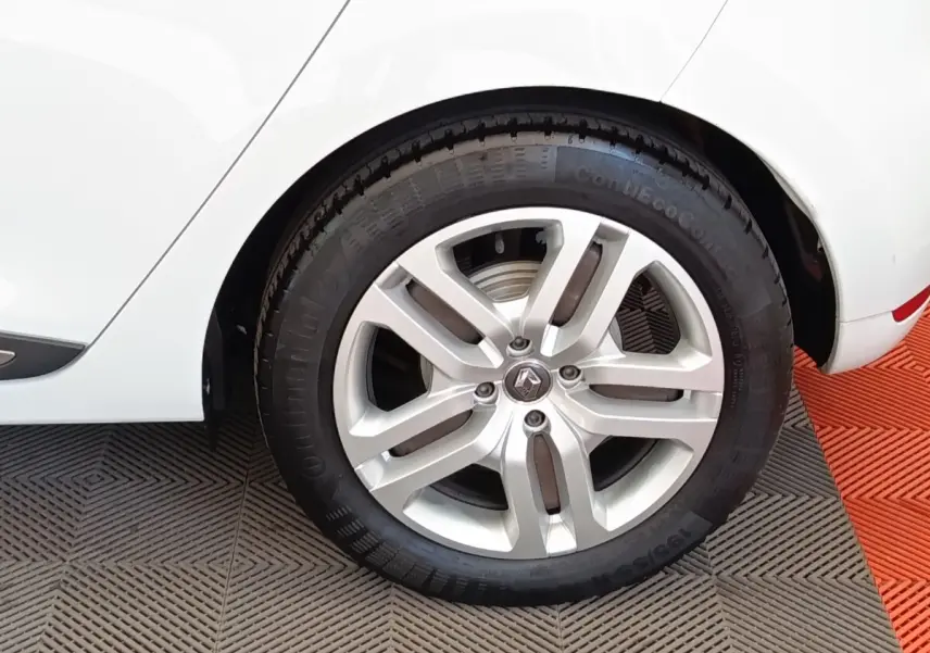 Gros plan sur la roue arrière droite d’une Renault Clio Business dCi 75 blanche, avec jante alliage et logo Renault visible.