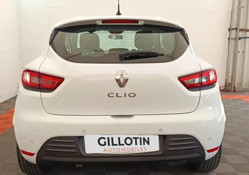 Vue arrière d'une Renault Clio blanche de 2018 avec feux arrière allumés et logo Renault visible.