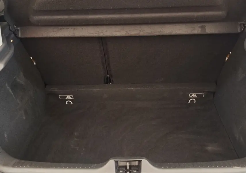 Coffre ouvert de la Renault Clio Business dCi 75 blanc, montrant l'espace de chargement vide et la moquette noire.