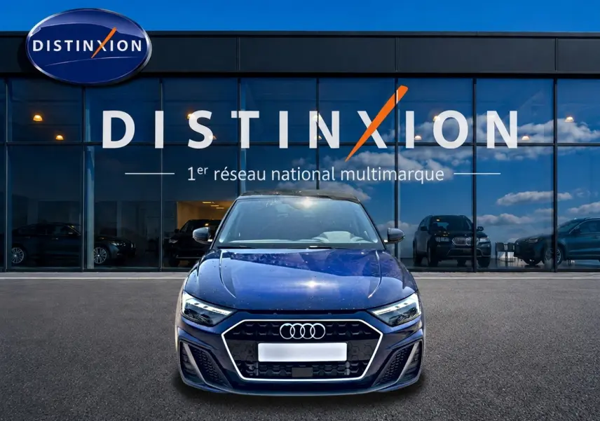 Audi A1 Sportback bleu foncé vue de face, avec calandre hexagonale et phares LED, devant un showroom Distinxion.