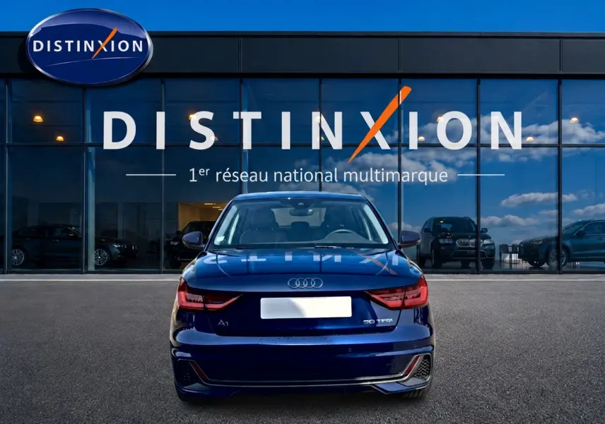 Vue arrière d'une Audi A1 Sportback 30 TFSI bleu foncé avec feux LED et becquet, devant une vitrine Distinxion.
